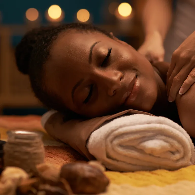 Woman laying with head on towel receiving a back massage.