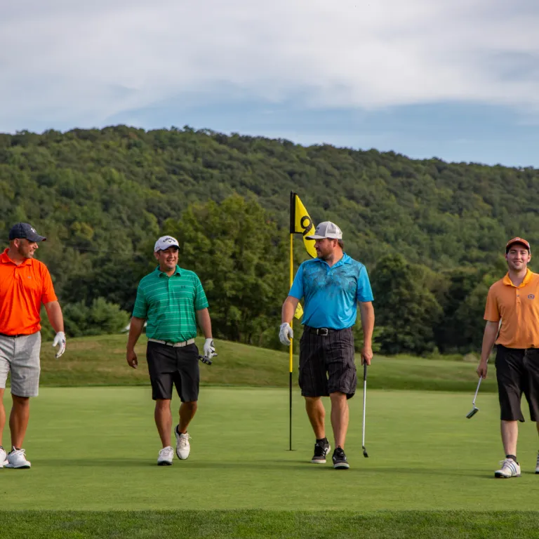 Four guys wearing multi-colored shirts walking on a golf course at a resort close to NYC