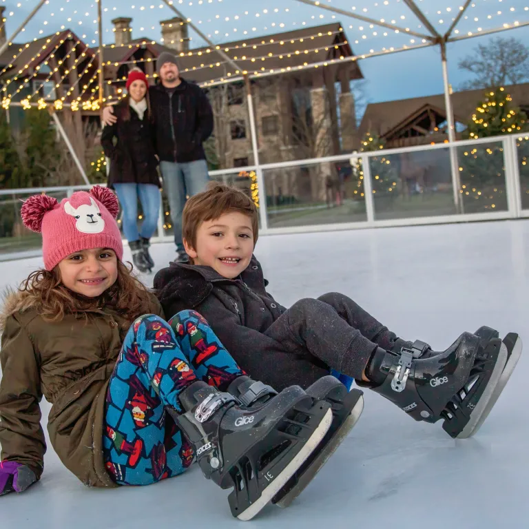 Kids sitting on glice skating rink.
