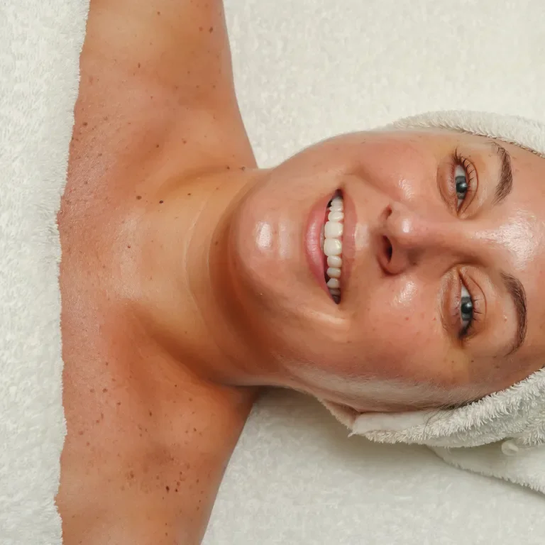 Woman laying on table in white hair towel smiling