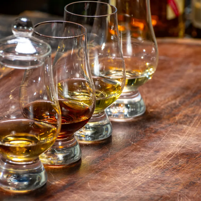 4 glasses filled partially with bourbon.