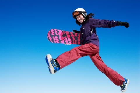 Snowboarder jumping against clear blue sky. 