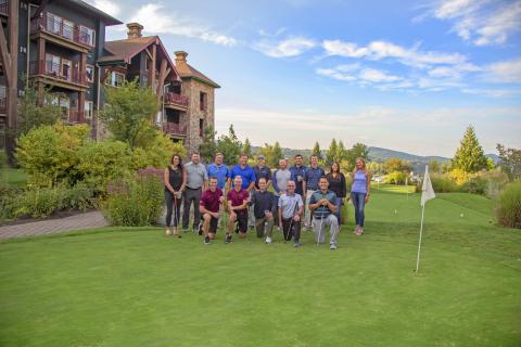 Group of people pose for photo on putting course.