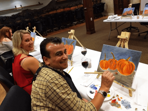 Group painting pumpkins on canvas. 