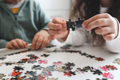 Children putting two pieces of a puzzle together. 