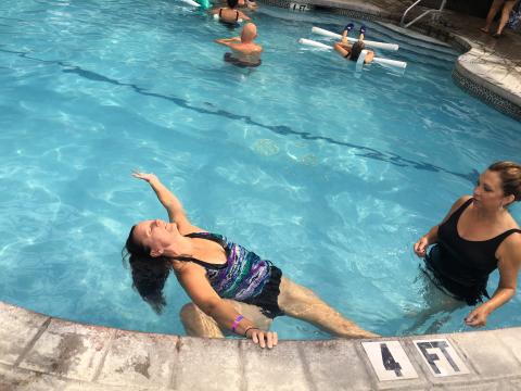 Woman stretching backwards into pool during aqua yoga