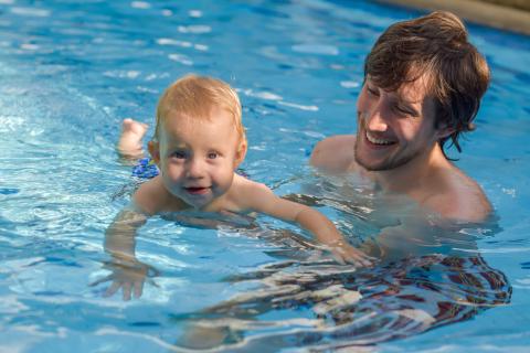 Man holding baby in pool
