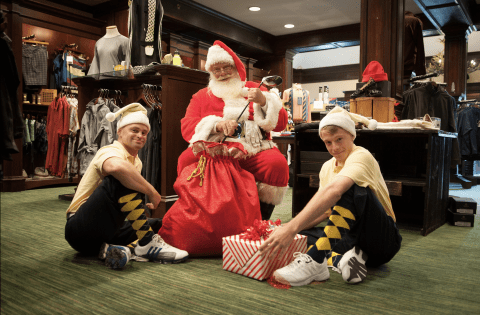 Two men dressed as elves with Santa and his sack of presents in the Crystal Springs Pro Shop 
