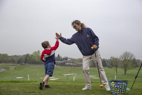 Young boy high-fiving after golf lesson