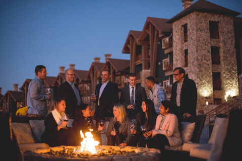 A corporate group meeting and having drinks by a firepit at a resort close to New York City