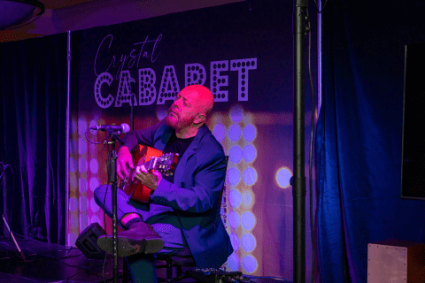 Hernan Romero playing guitar on stage at Crystal Cabaret.