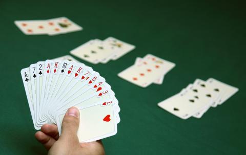 Hand holding spread out playing cards.