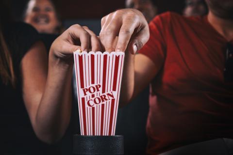 Two hands reaching in to popcorn holder.