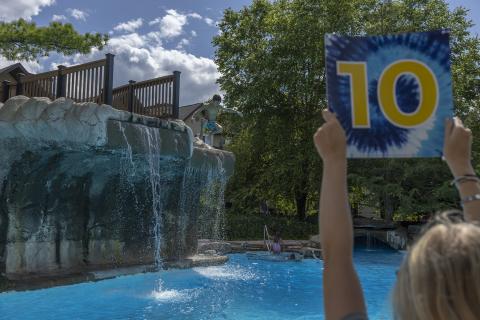 Lifeguard holding tie dyed sign with the number 10 displayed.