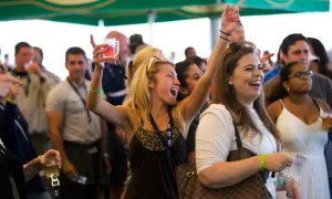 Woman with beer tasting in her hand singing at NJ Beer and Food Festival.