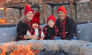 Family of four sitting around firepit during a snow storm.
