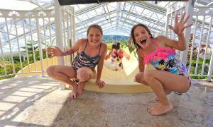 Two girls at top of Biosphere pool complex indoor slide.
