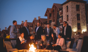 A corporate group meeting and having drinks by a firepit at a resort close to New York City