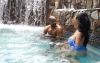Couple sitting in hot tub next to waterfall at Minerals Hotel Pool Complex 