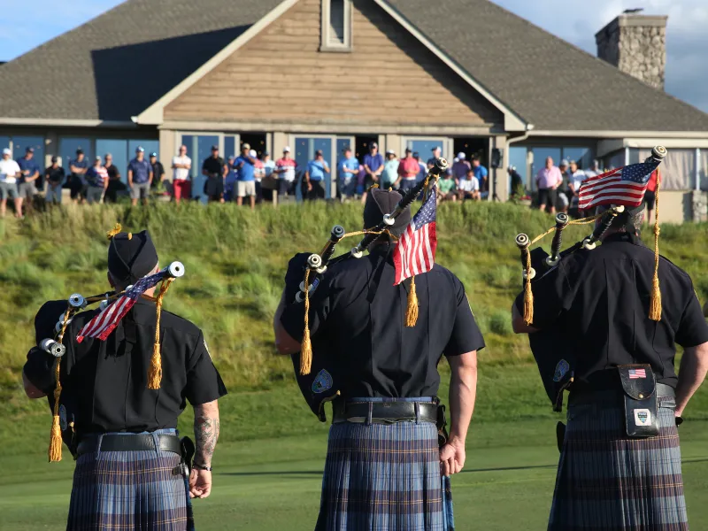 Bagpipers stand with American flags facing towards Ballyowen Clubhouse