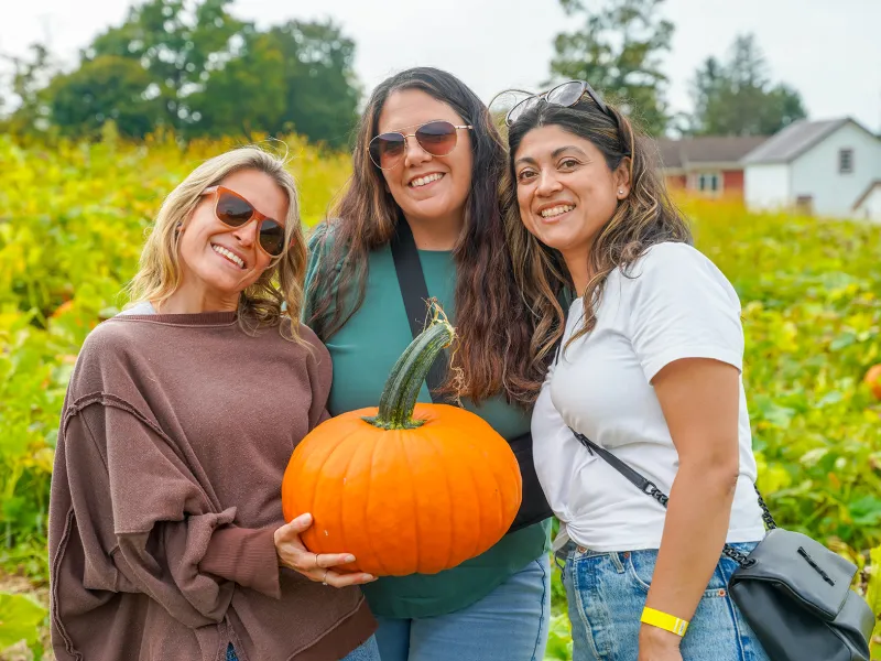 Three girlfriends at pumpkin patch.