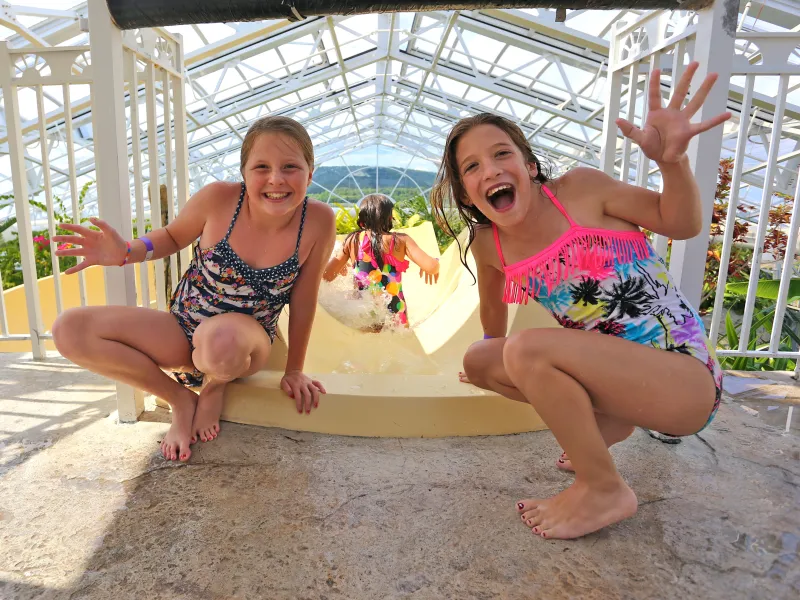 Two girls at top of Biosphere pool complex indoor slide.