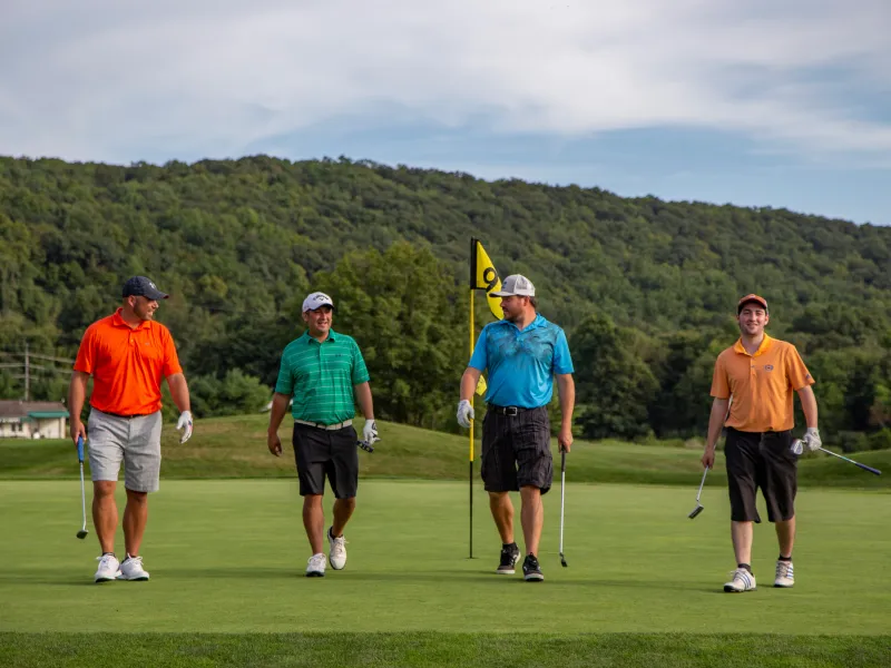 Four guys wearing multi-colored shirts walking on a golf course at a resort close to NYC