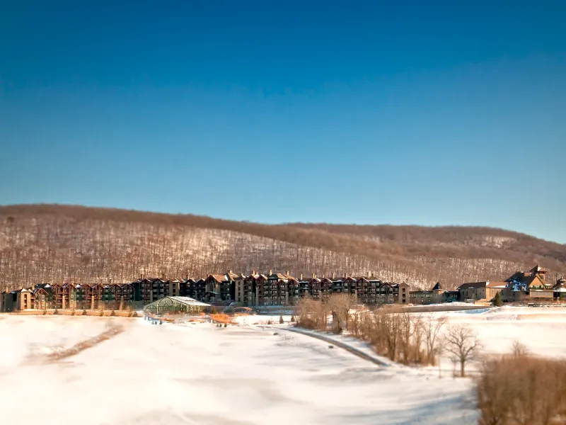 Distant view of Grand Cascades Lodge in front of the snowy mountains