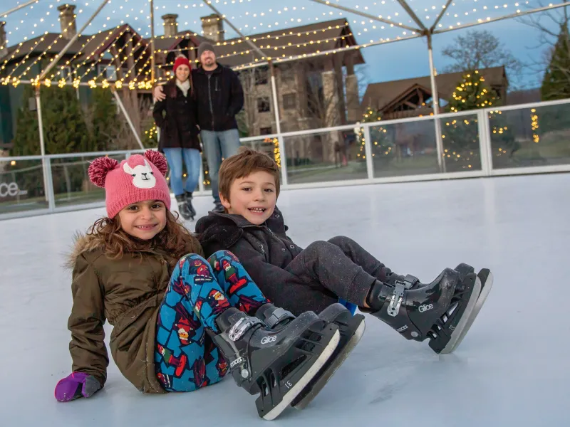 Kids sitting on glice skating rink.