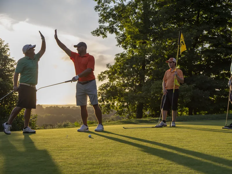 Men high fiving on putting green